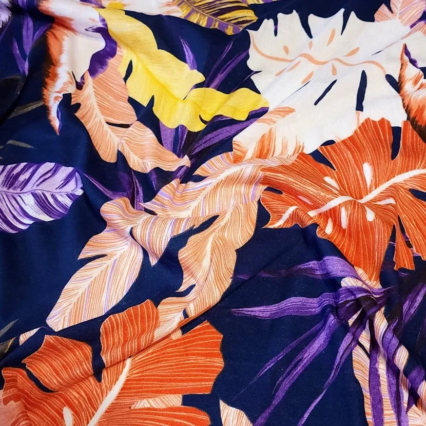 Lightweight Cotton Knit Fabric, Pretty Purple, Coral, and Yellow Tropical Print on Navy. 2-way stretch. Sold by the 1/2 yard